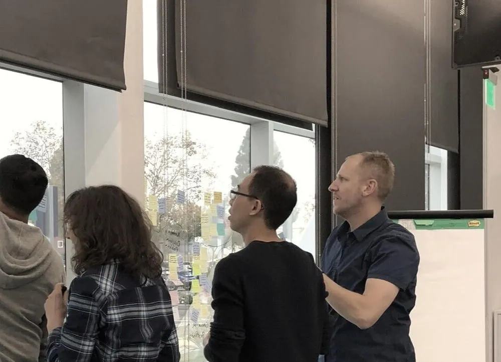Marc Krejci and three colleagues placing sticky notes on a window during a product workshop.
